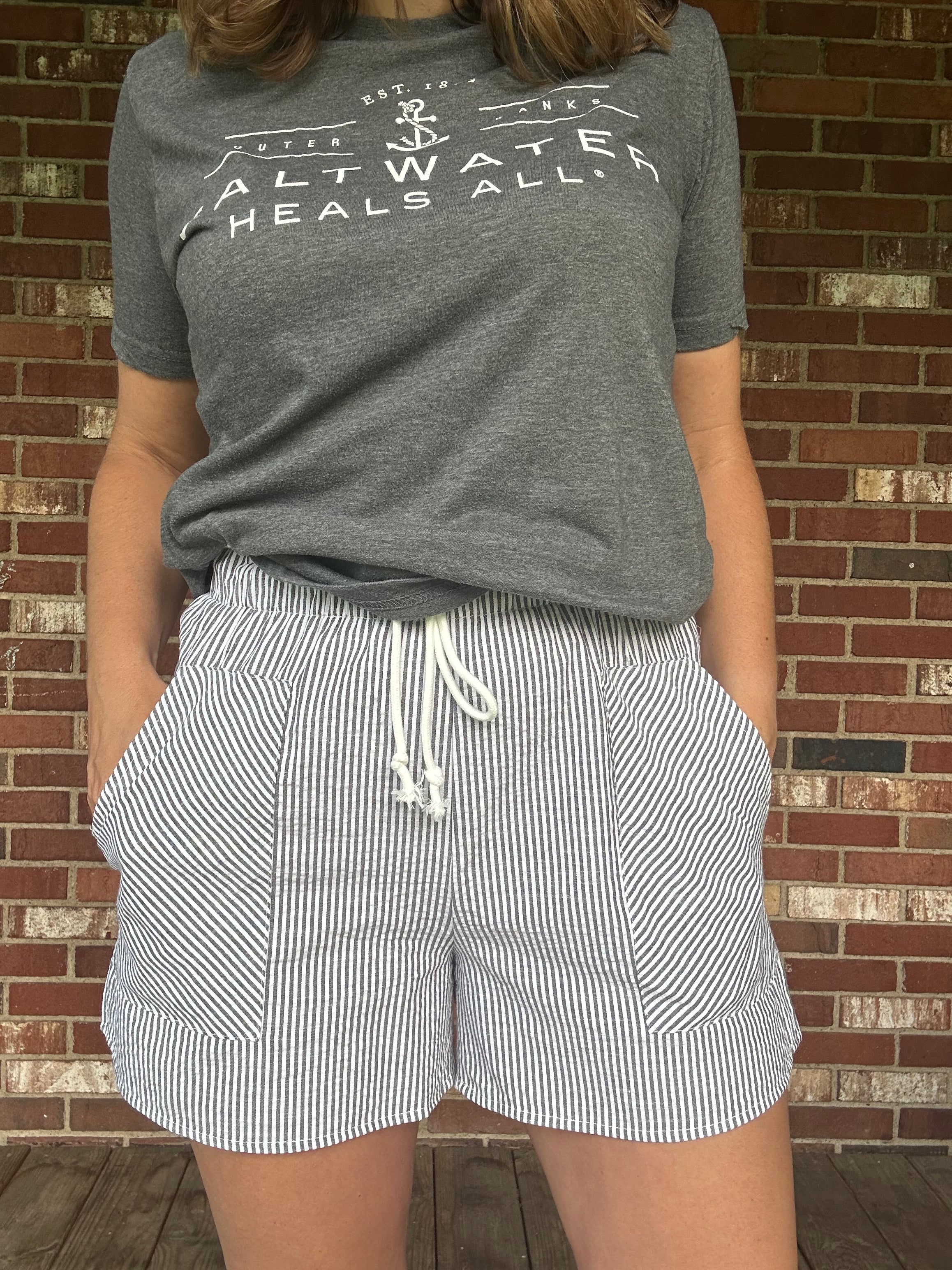 Model wearing navy and white seersucker stripe drawstring shorts with elastic waist and side pockets